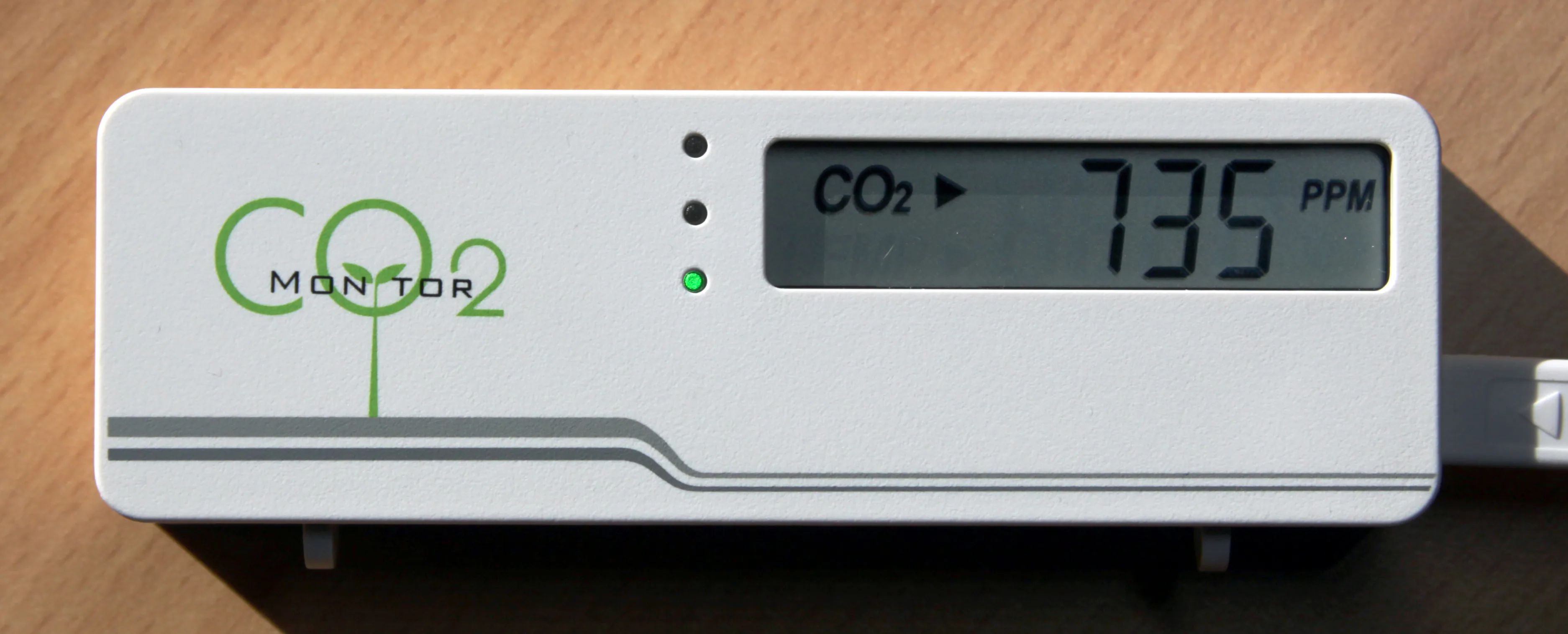 桌面 NDIR 二氧化碳監測器顯示 735 ppm 的真實照片，示意選擇可記錄 ppm 趨勢的量測工具