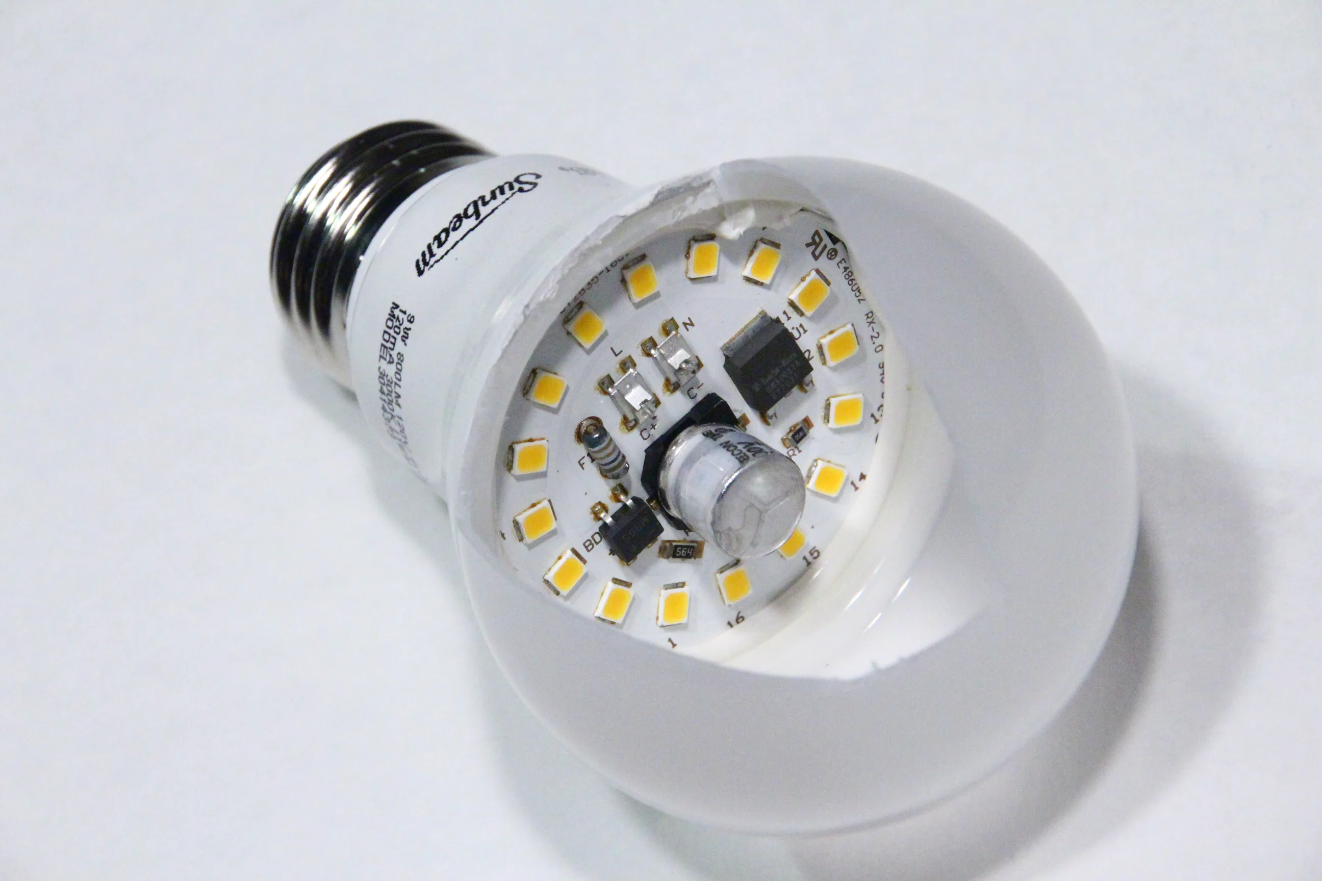 拆開外罩後可見 LED 燈泡內部電路的真實照片，用於說明驅動與光源可能是故障成本來源