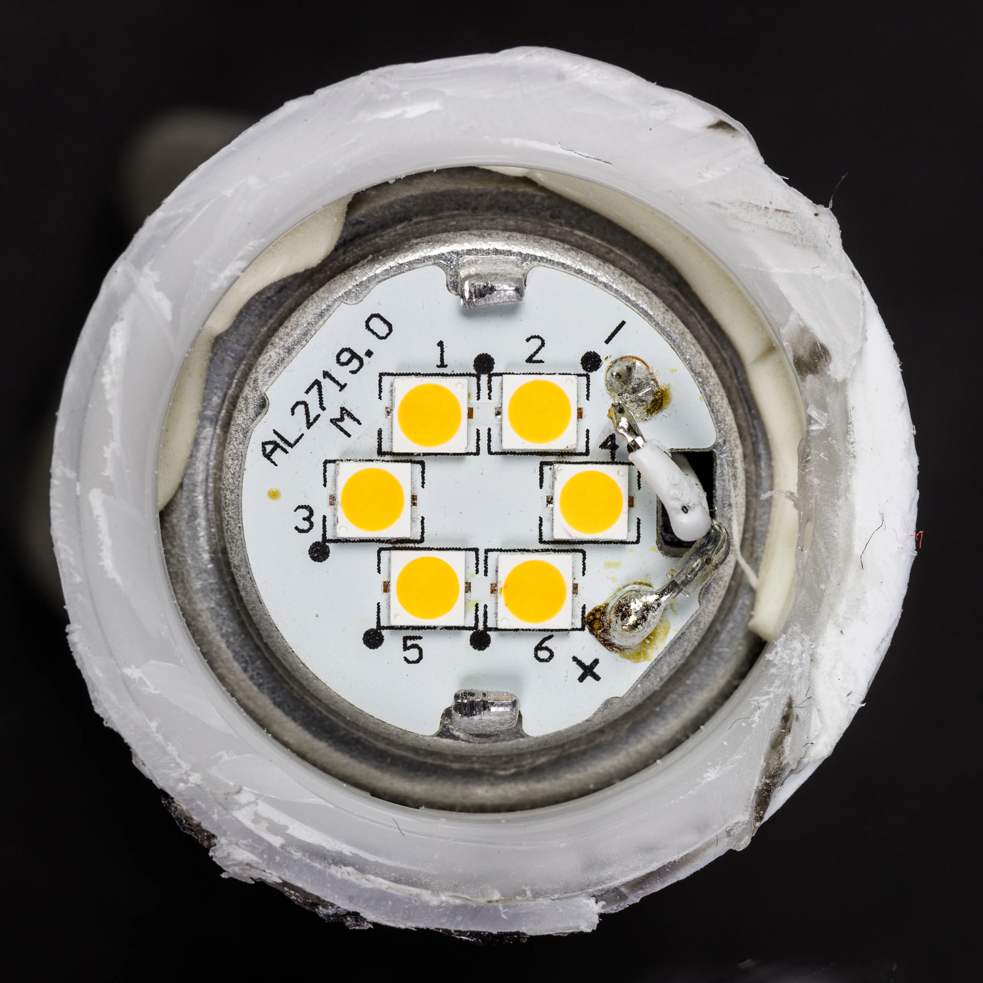 切開的 E14 LED 燈泡真實照片，顯示燈珠板與擴散罩，僅作白光 LED 結構示意