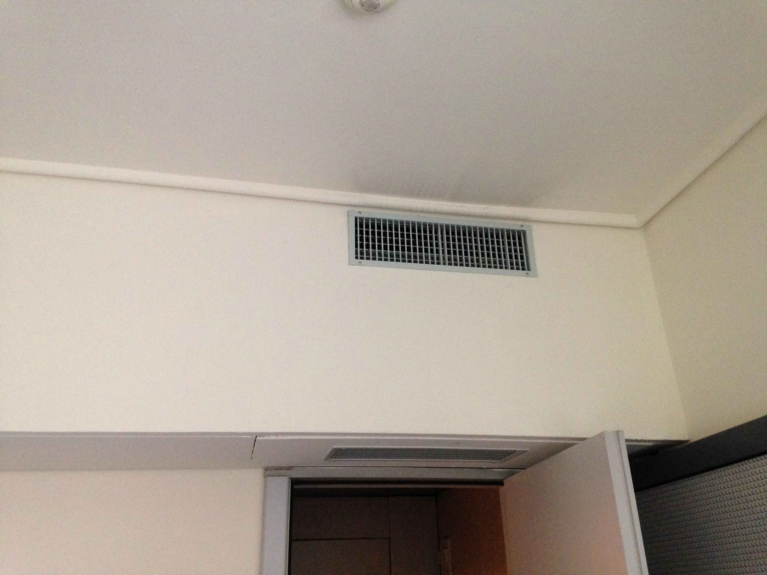 真實臥室空調出風口照片，示意先辨認出風、回風與家具遮擋，不代表台灣分離式冷氣型號