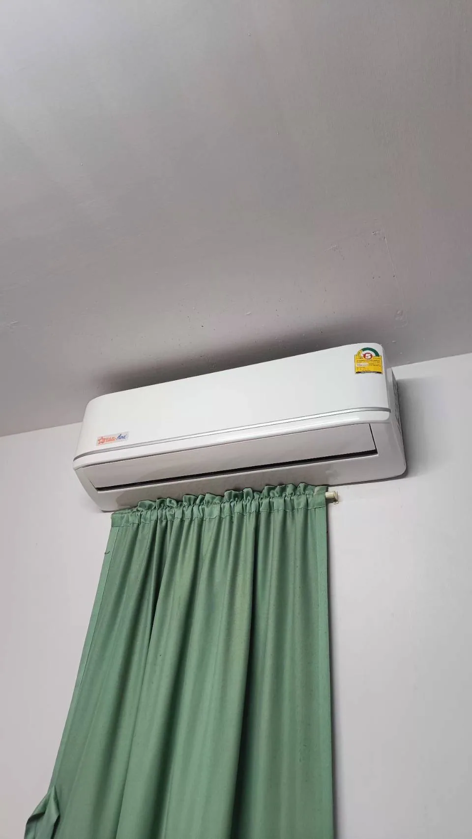 真實室內冷氣裝在窗簾上方的照片，示意窗簾垂長、進出風與機身周邊空間要一起檢查